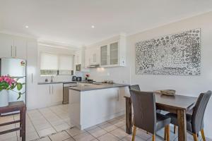 a kitchen with white cabinets and a table and chairs at Surf Sea and Sand in East Ballina +4 photos