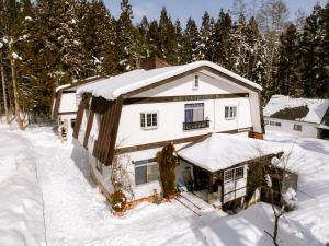 a house covered in snow with trees at sneaky peaks in Hakuba
