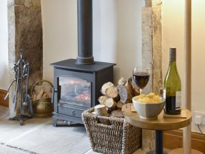 a table with a glass of wine and a wood stove at Rose Cottage - Uk34067 in Grassington