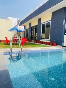 a swimming pool with two chairs and an umbrella at villa Belmond with private pool in Udaipur