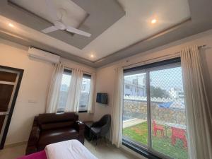 a bedroom with a ceiling fan and a bed and a window at villa Belmond with private pool in Udaipur