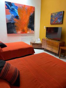 a room with two beds and a flat screen tv at LARIMAR Gallery y Hotel Boutique in Oaxaca City