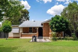 a brick house with a dog sitting in the yard at Ironbark Oasis - Serene Poolside Haven by Mudgee CBD in Mudgee