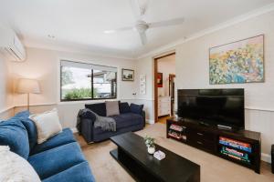 a living room with a blue couch and a flat screen tv at Ironbark Oasis - Serene Poolside Haven by Mudgee CBD in Mudgee