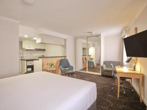 a hotel room with a bed and a desk and a kitchen at Rendezvous Hotel Sydney The Rocks in Sydney