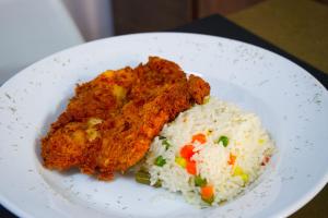 a white plate of food with rice and chicken at Hostal Estadio Nacional in Santiago