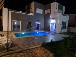 a house with a swimming pool at night at Dar fadloun in Midoun