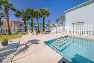 a swimming pool with palm trees and a white fence at Sea the Good in Panama City Beach