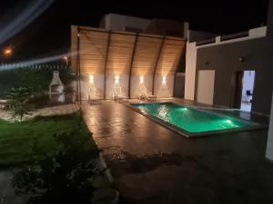 a swimming pool at night with chairs around it at Dar fadloun in Midoun