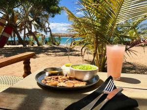 a plate of food on a table with a drink at Upali Beach Surf Resort in Nikawatawana
