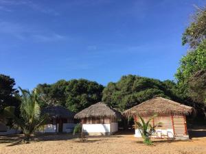 a couple of huts on a beach with trees at Upali Beach Surf Resort in Nikawatawana