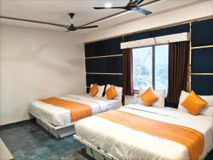 two beds in a room with a window at Hotel Karnavati Motera Ahmedabad in Ahmedabad