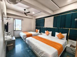 a hotel room with two beds and a television at Hotel Karnavati Motera Ahmedabad in Ahmedabad