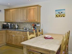 eine Küche mit einem Holztisch und Holzschränken in der Unterkunft Methodist Cottage in Tantobie
