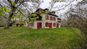 an old house with a red door in a field at Maison des bois in Château-Chervix
