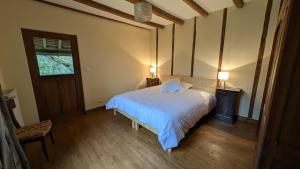 a bedroom with a white bed and a window at Maison des bois in Château-Chervix