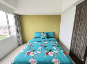 a bedroom with a blue bed with flowers on it at Studio Bogor Icon Apt wifi&pool in Kedunghalang