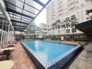 a large swimming pool in a building with tables and chairs at Studio Bogor Icon Apt wifi&pool in Kedunghalang