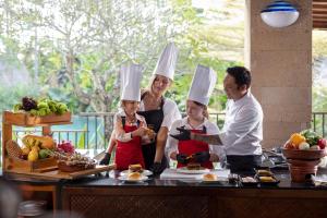 a family wearing chefs hats preparing food in a kitchen at Sanctoo Suites & Villas in Gianyar +19 photos