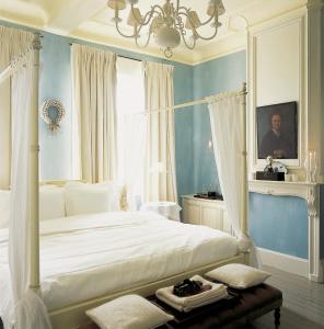 Schlafzimmer mit einem weißen Bett und einem Kronleuchter in der Unterkunft Hotel Recour in Poperinge