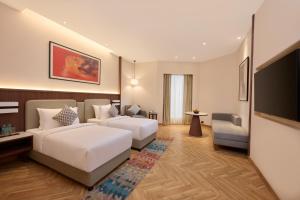 a hotel room with two beds and a flat screen tv at Skywings Sarovar Portico Mathura in Mathura