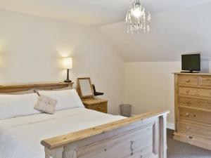 ein Schlafzimmer mit Bett, Fernseher und Kommode in der Unterkunft Methodist Cottage in Tantobie
