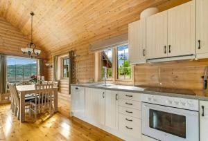 a kitchen with white cabinets and a dining room with a table at Cabin With Jacuzzi And Stream In Krågeland in Kvinlog