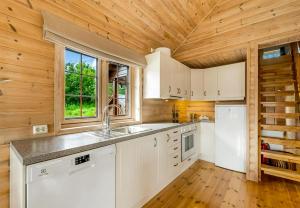 a kitchen with white cabinets and a wooden ceiling at Cabin With Jacuzzi And Stream In Krågeland in Kvinlog