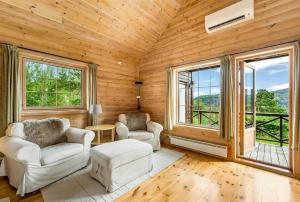 a living room with two chairs and two windows at Cabin With Jacuzzi And Stream In Krågeland in Kvinlog +29 photos