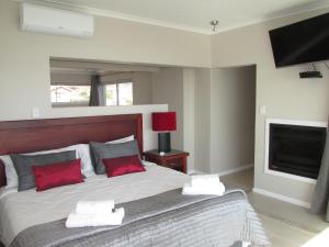a bedroom with a bed with red pillows and a television at Belle Mer Guest House in Pringle Bay