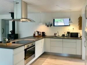 a kitchen with white cabinets and a sink at Summer House 300 M From Beach in Hals