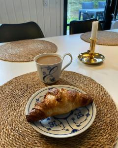 a plate with a croissant and a cup of coffee at Summer House 300 M From Beach in Hals +30 photos