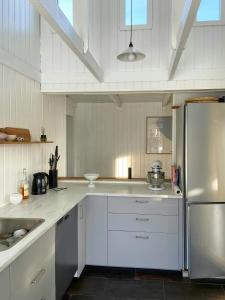 a kitchen with white cabinets and a stainless steel refrigerator at Architect-Designed Cottage By The Water in Middelfart
