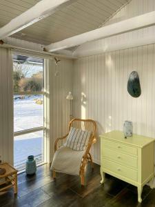a room with a chair and a dresser and a window at Architect-Designed Cottage By The Water in Middelfart