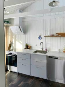 a white kitchen with a sink and a stove at Architect-Designed Cottage By The Water in Middelfart