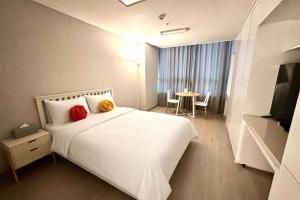 a bedroom with a white bed with two red pillows at 더 디셈버스테이 인 한라 in Taeam