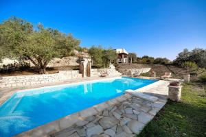 een zwembad in een tuin met een huis op de achtergrond bij Villa Margi in Giarratana