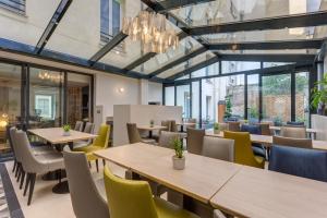 um restaurante com mesas, cadeiras e janelas em Jardin de Villiers em Paris