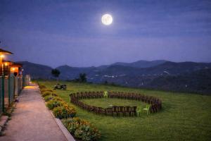 a moon over a garden with a pond in a field at The Bowers Chalet Private Campfire & Lawn BBQ, WIFI, Breakfast Hill Top 360 degree view in Ooty +22 photos