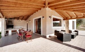 een patio met een tafel en stoelen en een houten plafond bij Villa Margi in Giarratana