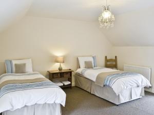 ein Schlafzimmer mit zwei Betten und einem Kronleuchter in der Unterkunft Methodist Cottage in Tantobie