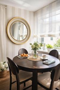 a round dining room table with chairs and a mirror at Downtown Boulevard View Residence in Šiauliai