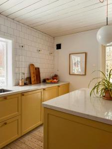 a kitchen with yellow cabinets and a white counter top at Cosy House Surrounded By Nature in Diö +9 photos