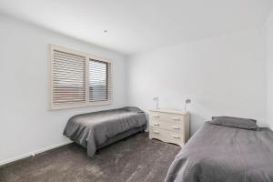 a white bedroom with two beds and a window at Andrea and Nigel's Beach House in Cape Woolamai +10 photos