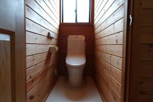 a bathroom with a toilet with wooden walls and a window at コテージZen in Kyotango