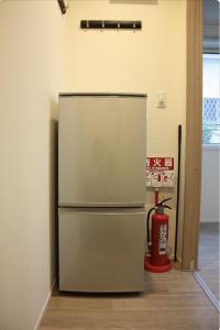 a refrigerator in a room with a fire extinguisher at Jasmine House in Tokyo