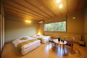 a room with two beds and a table and a window at Morinoryotei Biei in Biei