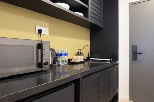 a kitchen with a counter top with a microwave at Stallionz Ipoh by ANGO in Ipoh