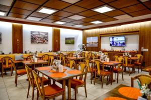 ein Restaurant mit Tischen, Stühlen und einem Fernseher in der Unterkunft Hotel Blauer Karpfen in Oberschleißheim