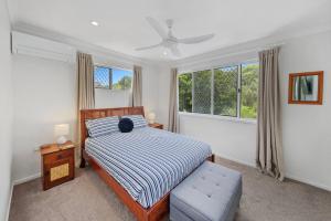 a bedroom with a bed and a chair and windows at Mudjimba Esp Villa-Beachfront-Pet friendly in Mudjimba